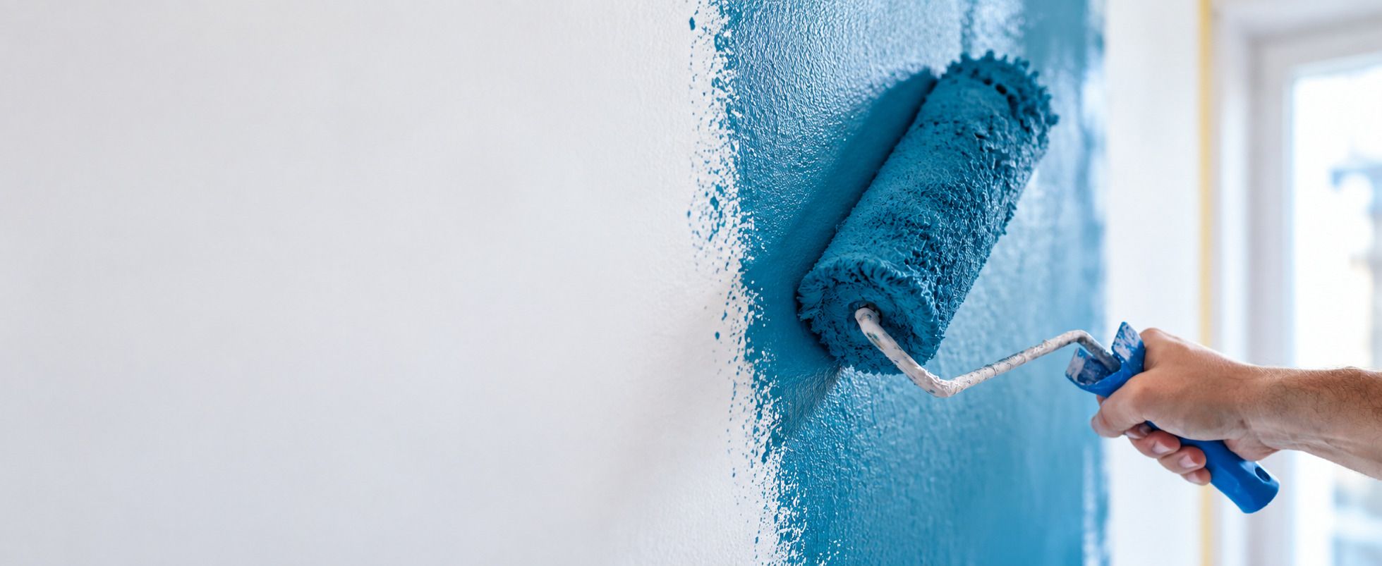 Malerrolle beim Streichen einer Wand in Blau